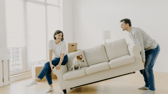 Couple playfully moving a couch