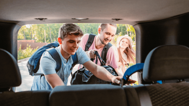 Young men putting bags in a vehicle